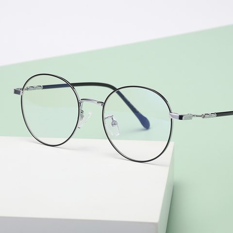 Thin round metal glasses frame in black and silver on a pale stand