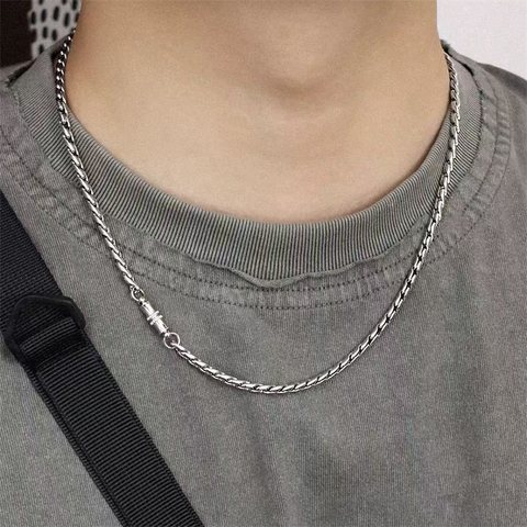 Twisted silver chain necklace with a magnetic clasp worn over a grey tee
