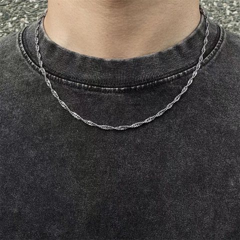 Thin silver water-wave chain necklace worn over a dark tee