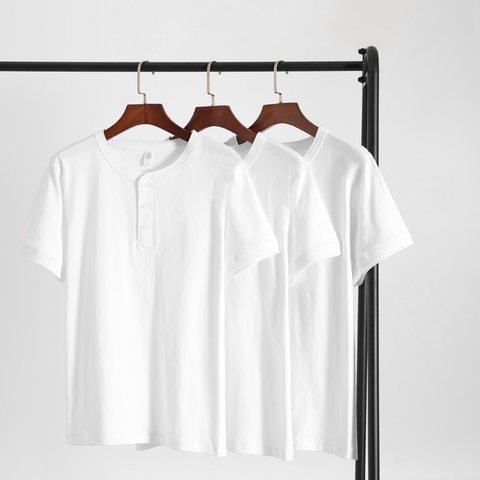 Three white short-sleeve Henley tees hanging on a rail