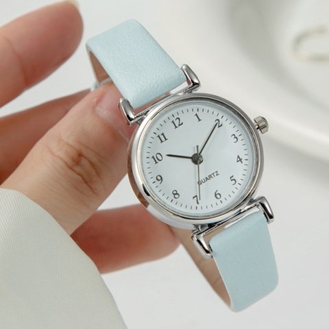 Small silver quartz watch with a light blue strap and numbered dial